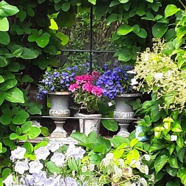 Bloemen en groen rondom een tuinspiegel